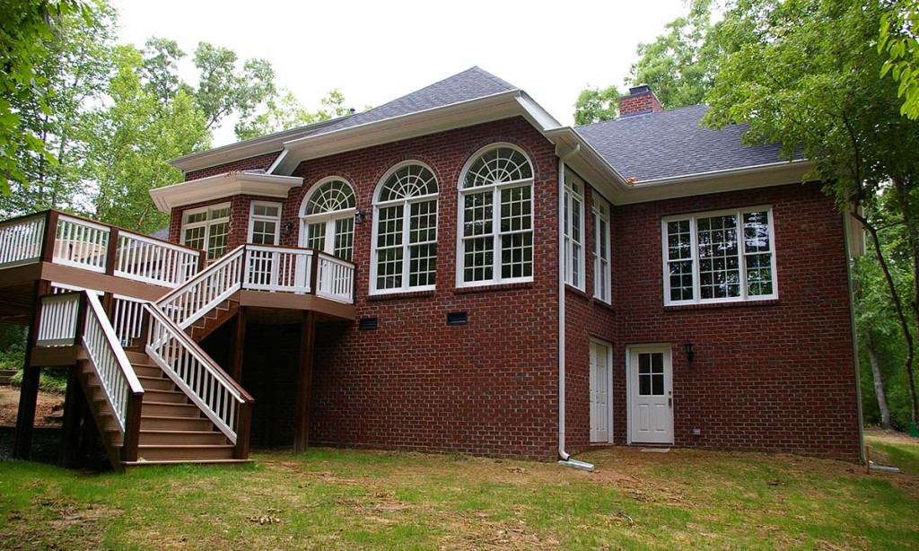 Exterior photo showing the new home with large two-story addition, deck and outside staircase