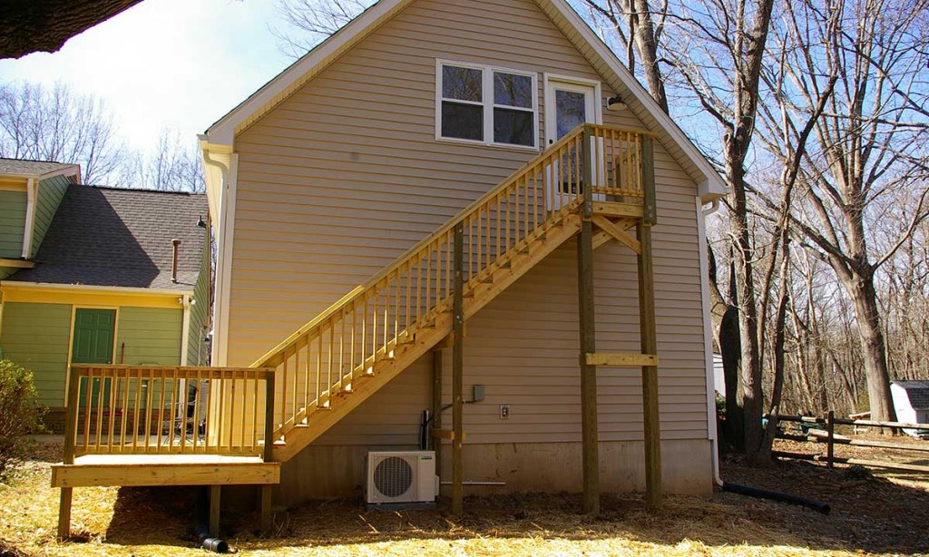 Back-facing photo of completed garage addition with deck and staircase leading to bonus room