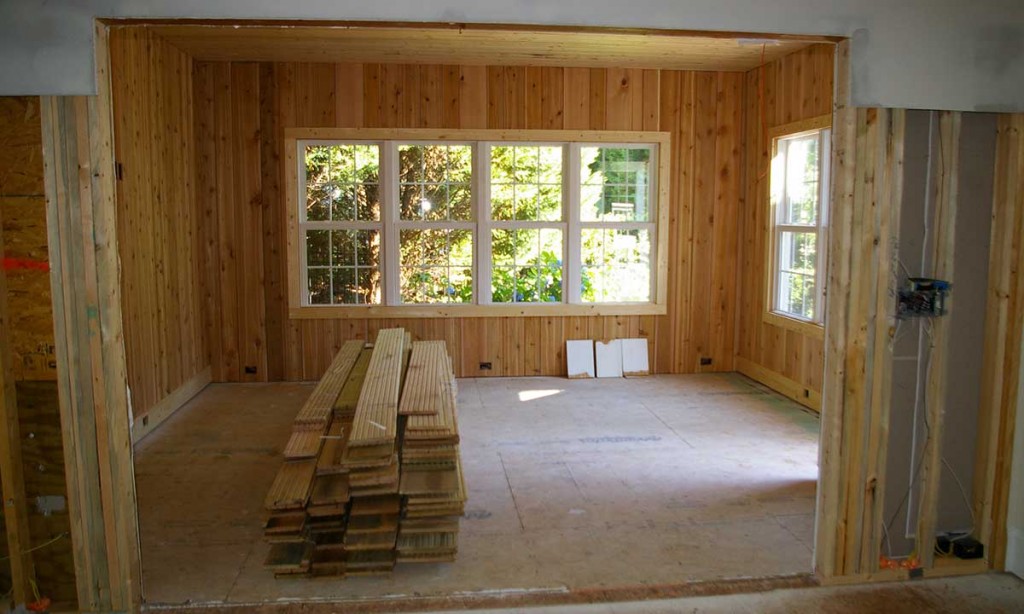 Interior view of the sunroom being built with reclaimed hardwood flooring for seamless flow between house and sunroom