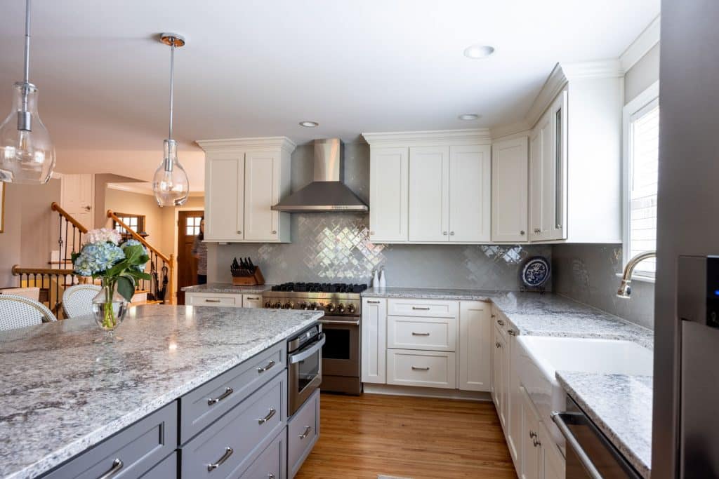 after photo of kitchen remodel with white cabinets and gray island with granite countertops