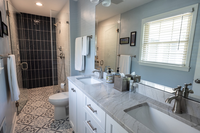 updated kitchen with dual sinks and stand up glass shower with blue tile