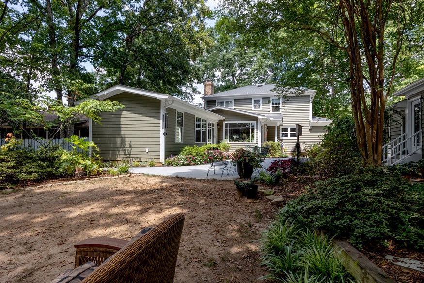 exterior of finished primary bedroom addition with manicured patio under shaded trees