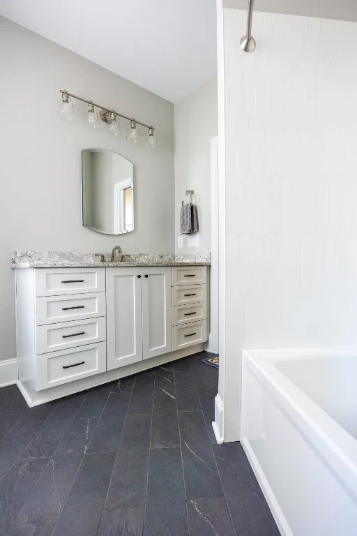 updated bathroom with white cabinets and tub shower in ADU