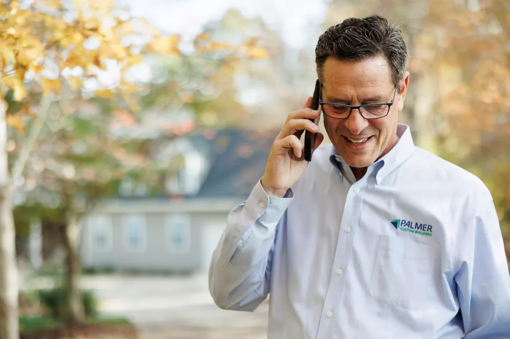 Gary Palmer on the phone smiling in front of completed remodeling project