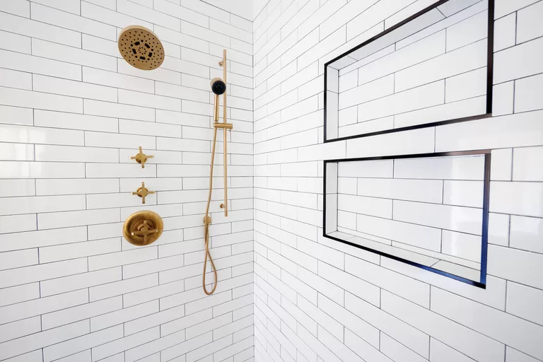 gold shower fixtures and white subway tile