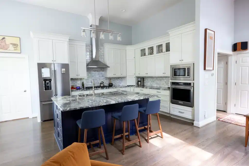 renovated blue island with white and gray granite countertops with blue bar stools