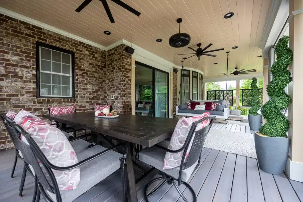 covered back patio with dining table, swing chair, and ceiling fans