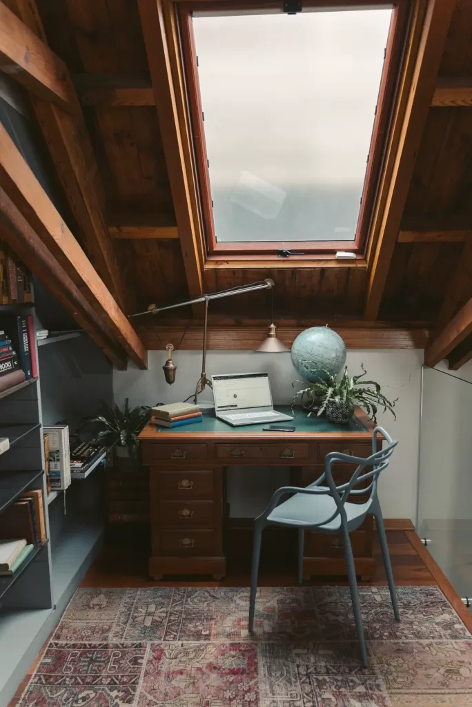attic converted into small home office with wooden desk and ceiling window
