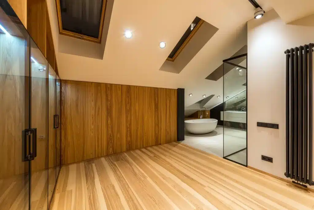 top floor (possibly attic) with wooden built in cabinets leading into a modern bathroom with separate bathtub