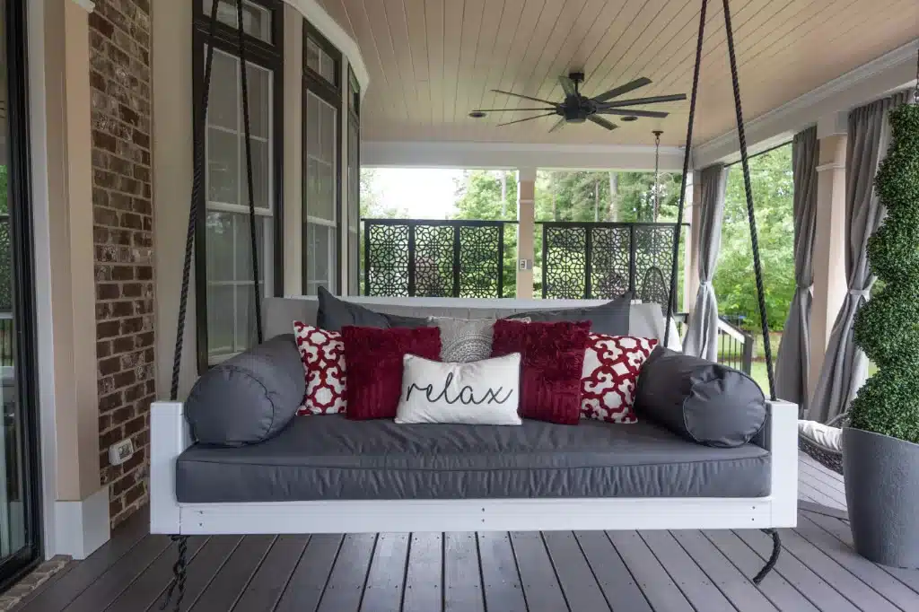 large hannging swing with gray cushions in newly remodeled back porch addition