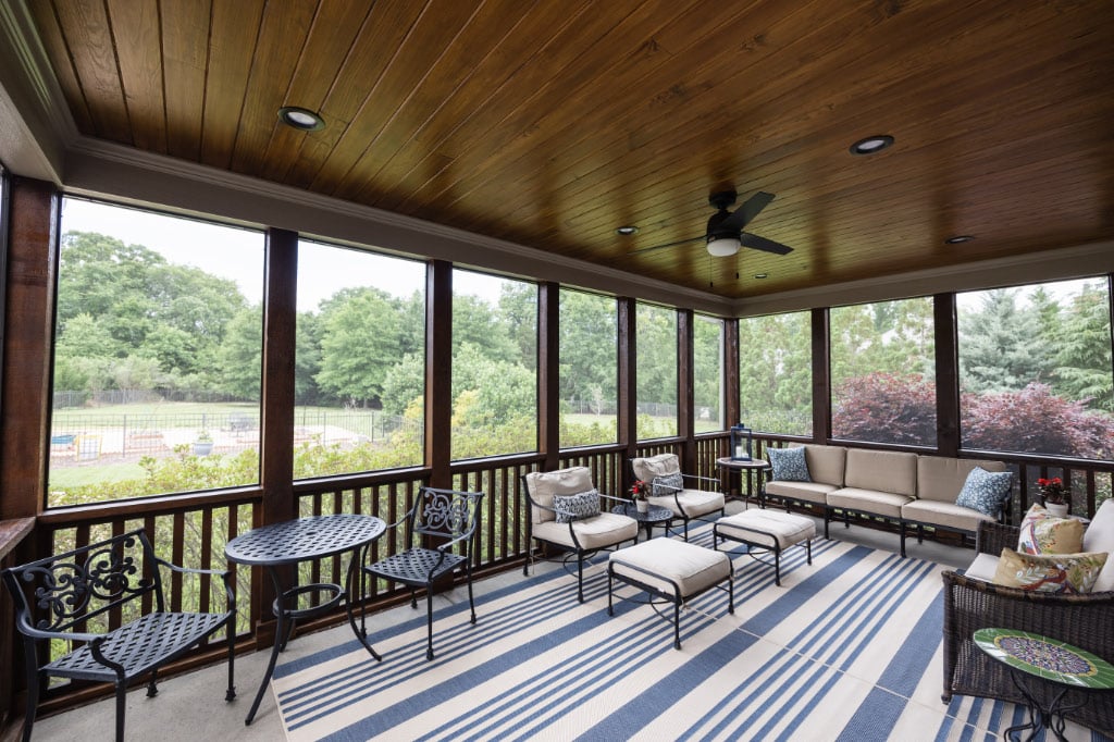 inside of screened-in porch with large patio rug and outdoor seats and couch