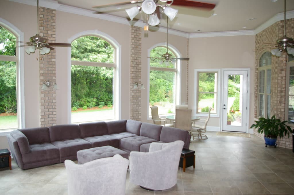 interior of high ceiling sunroom with exposed brick and floor to ceiling windows