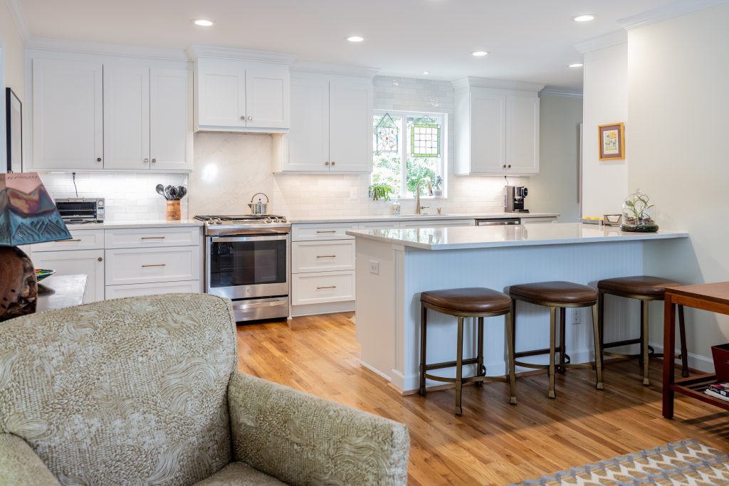 kitchen opens up to living area with a kitchen island with bar stools in between