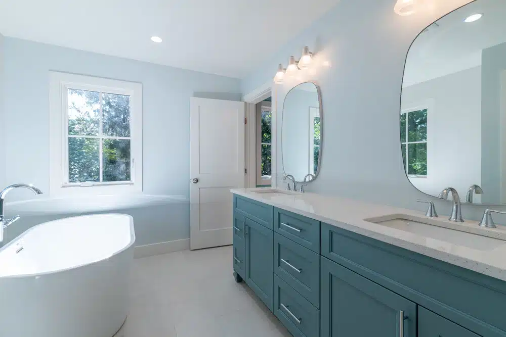 primary bathroom with stand alone bathrub, double sink, with blue pained cabinets and white quartz countertops