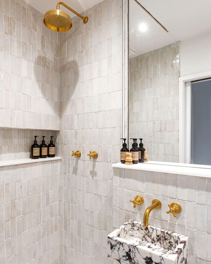 walk-in shower with mirror and sink inside with gold fixtures