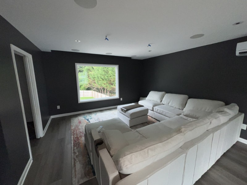 Movie room included in garage addition with pit-layout couch and projector tv
