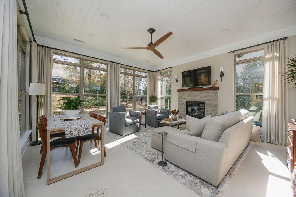 sunroom with ceiling fan and fireplace with tv above