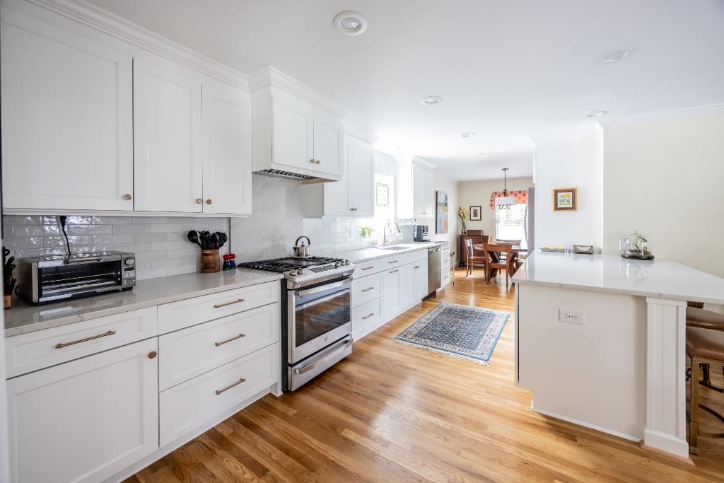 small kitchen remodel with white kitchen cabinets and white peninsula attached to wall with bar stools