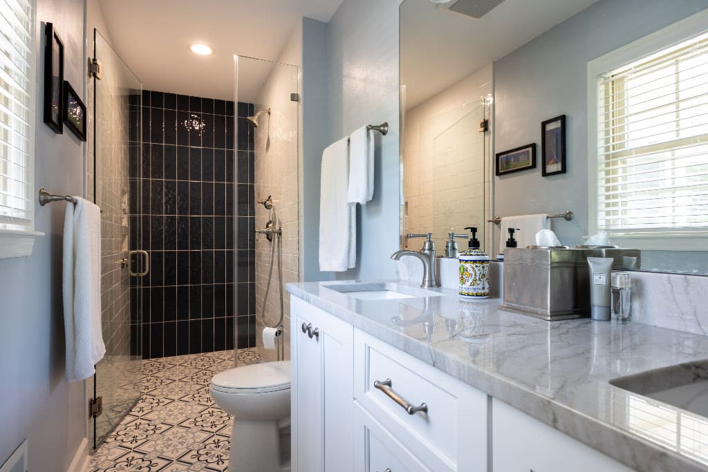 double vanity with marble countertop with walk in glass stand up shower, statement tile flooring, and one wall of slate tile in shower