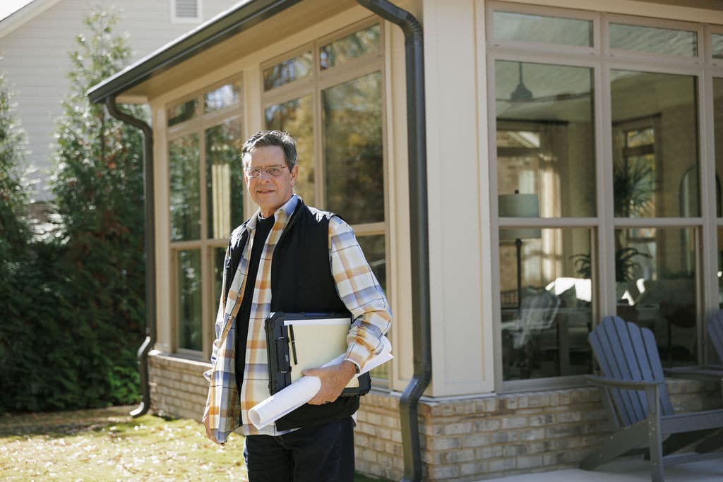 licensed general contractor Gary Palmer outside a home with planning documents in hand