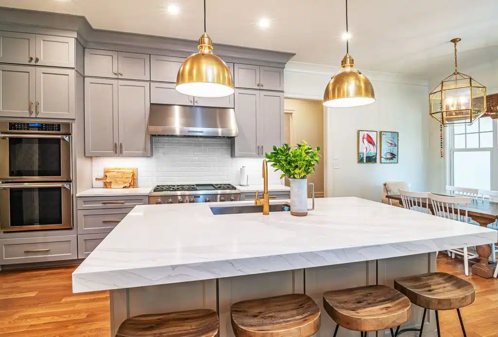 open style remodeled kitchen with white granite center island, gray cabinets that opens up to kitchen dining table next to island
