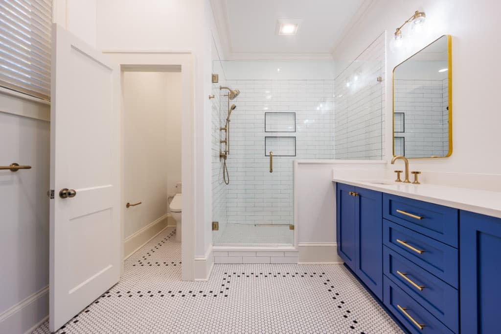 bathroom showing entry door opening towards wall on the right and vanity on walk in shower on left